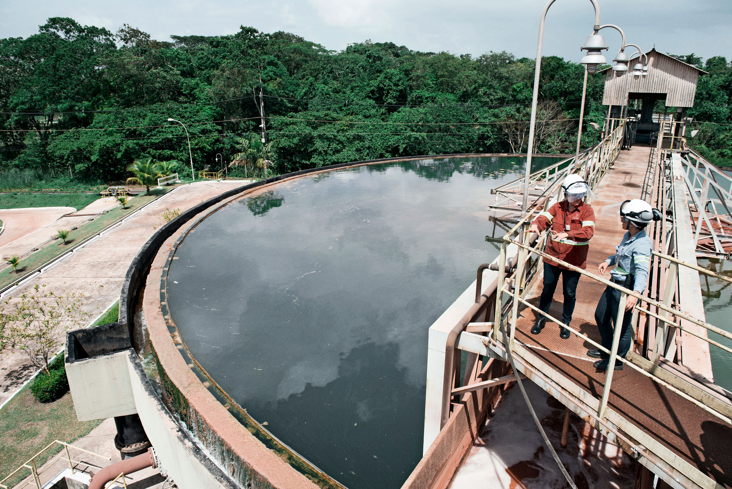 Two people talking on a metal bridge over a water tank