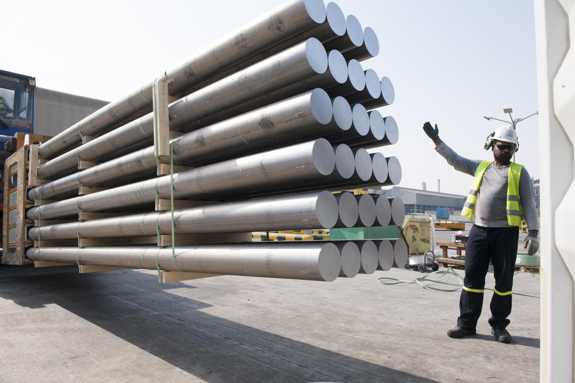 En Qatalum-ansatt dirigerer og klargjør pressbolt for transport. Pressboolt er råmaterialet for ekstruderte profiler.