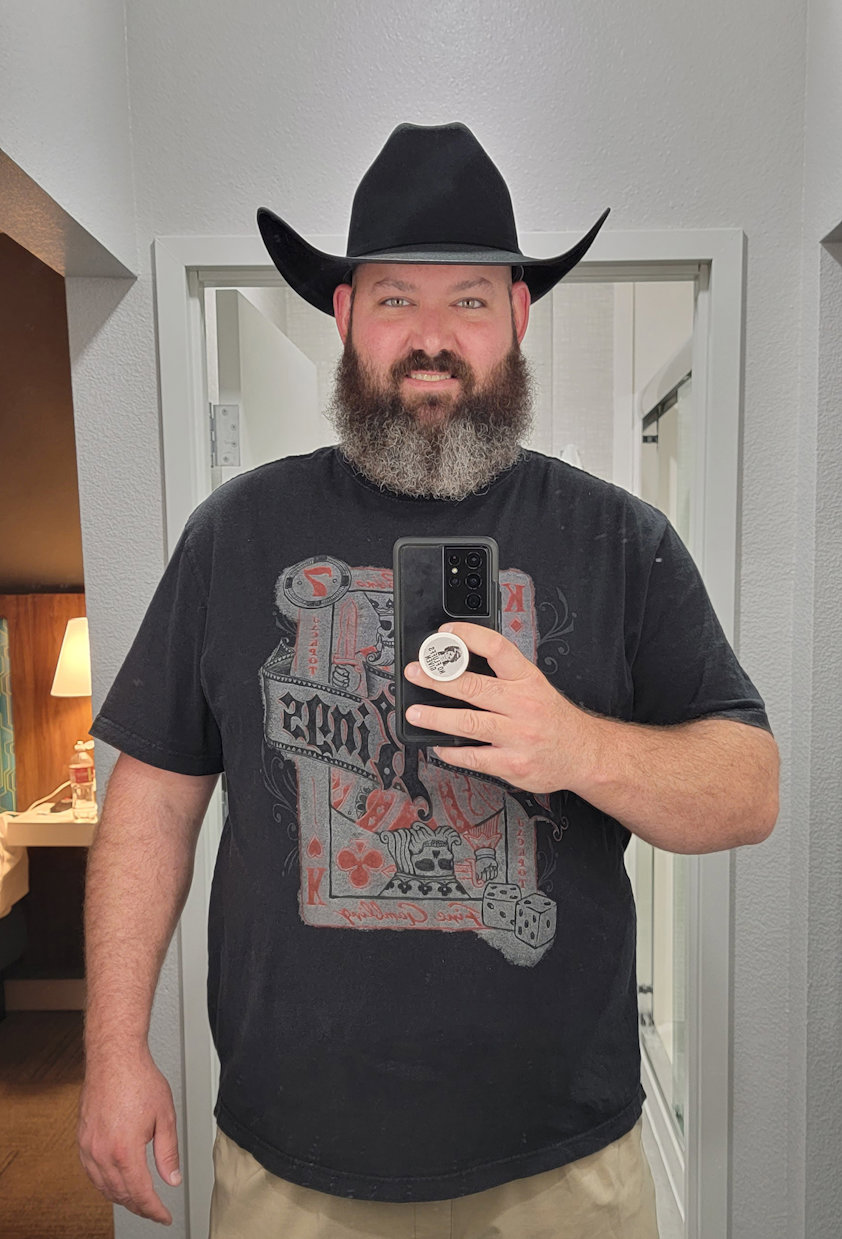a man wearing a cowboy hat and holding a cell phone