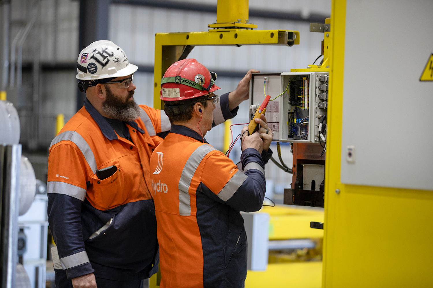 men in orange jackets and helmets working on a machine