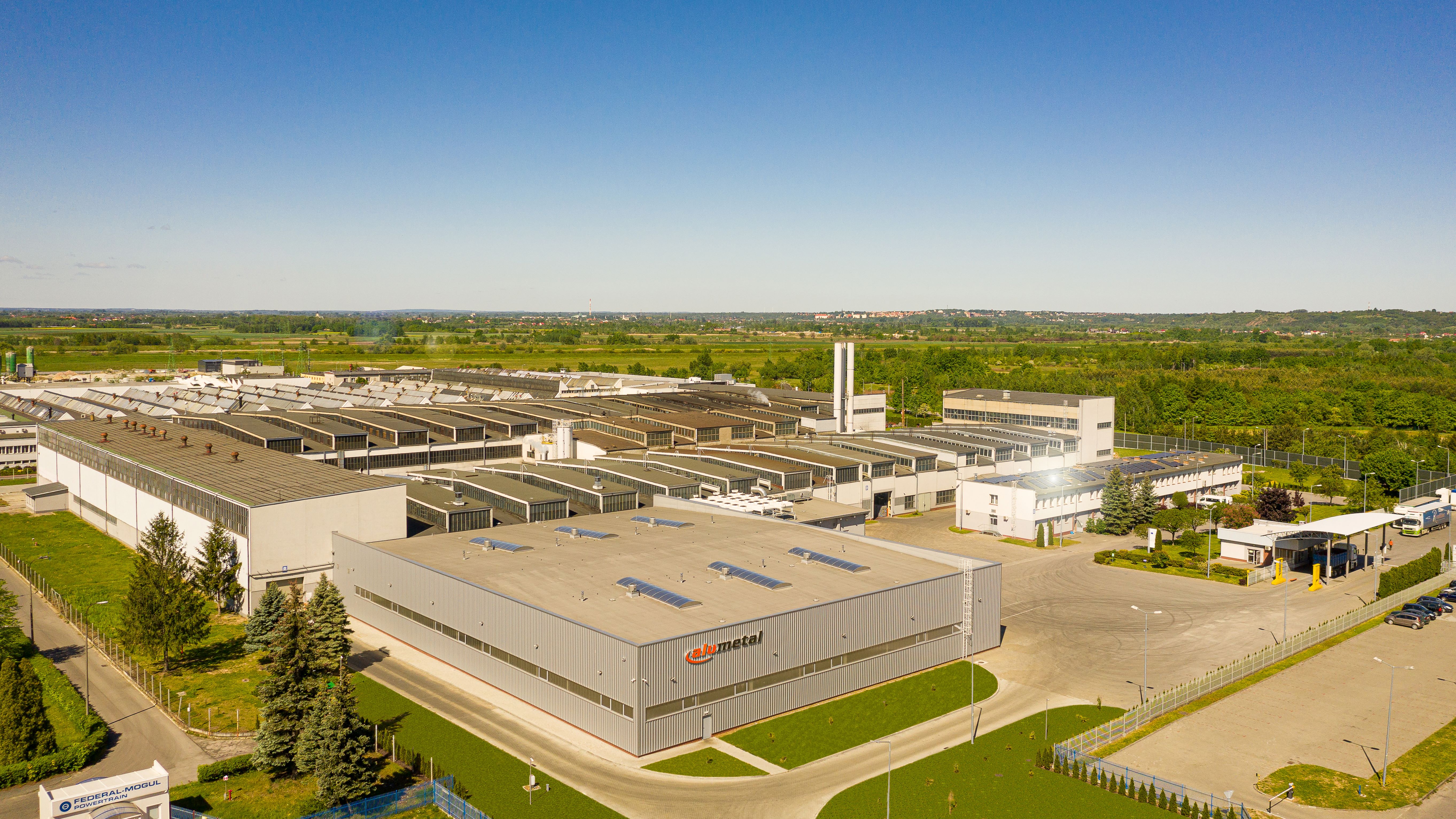 a large factory with trees and grass