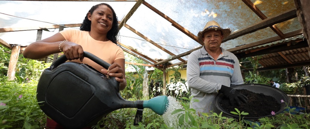 a woman and a man sitting under a straw hut